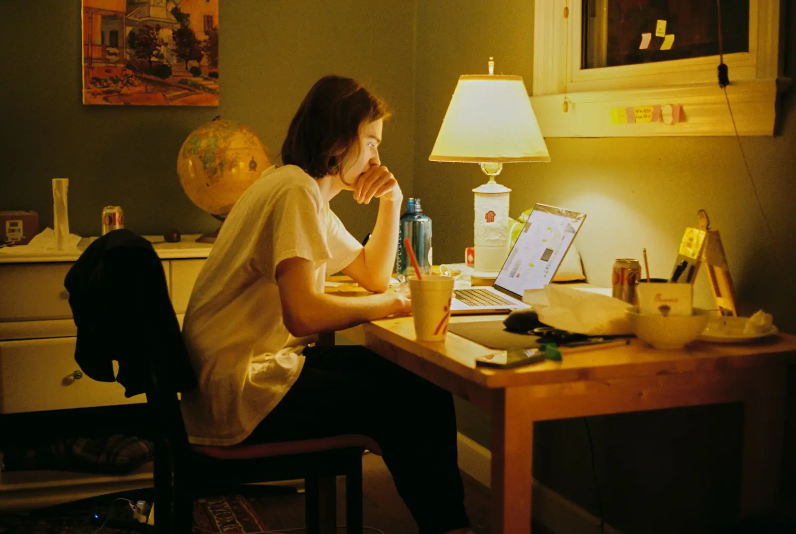 Person arbeitet abends am Laptop im warmen Licht einer Tischlampe